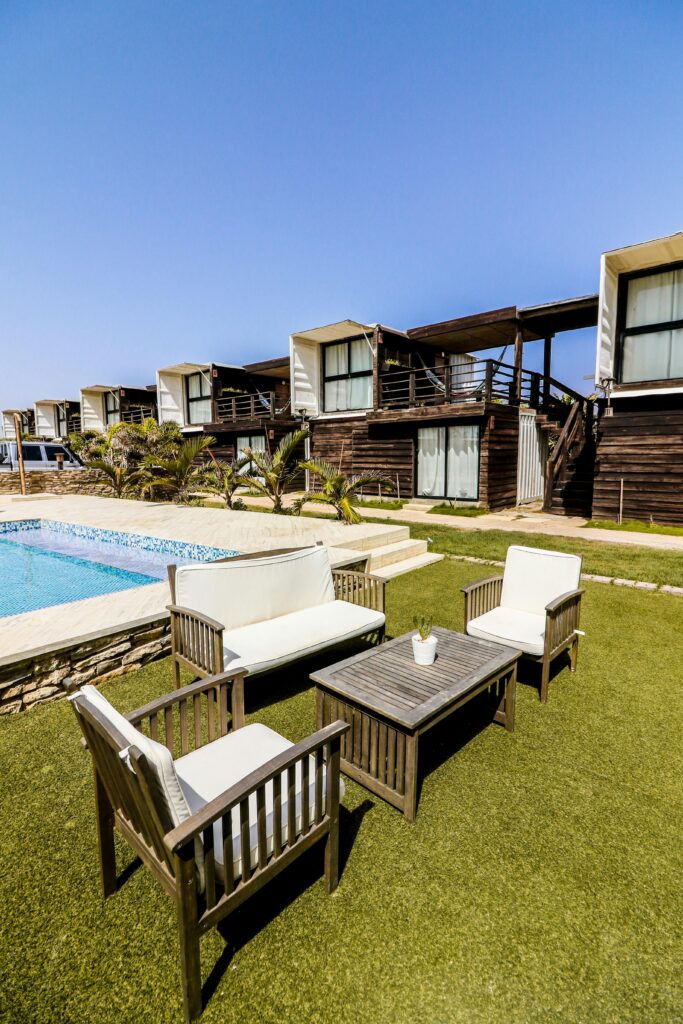 Elegant wooden furniture by a poolside with modern villas, under a bright blue sky in Adicora, Venezuela.