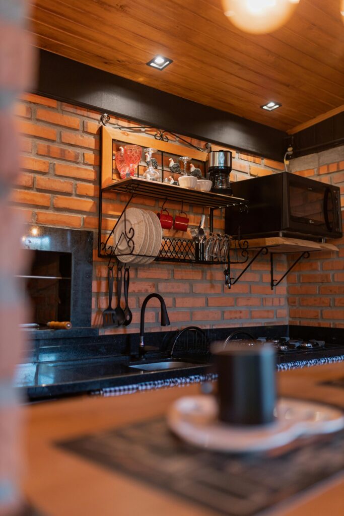 Warm and inviting kitchen featuring rustic brick walls, wooden shelves, and modern appliances.